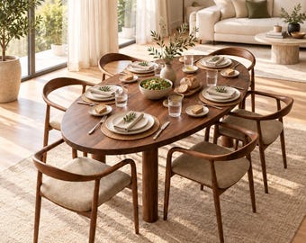 May include: An oval dark wood dining table with six matching chairs featuring curved backrests and beige upholstered seats. The table is set with white plates, linen napkins, glassware, and a central bowl of salad and bread.