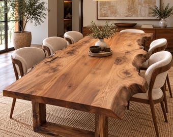 May include: A large live edge dining table made of natural brown wood with a prominent grain and knots, supported by a sturdy rectangular base. The table is surrounded by six chairs featuring curved wooden frames and light beige upholstered seats.