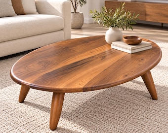 May include: An oval coffee table crafted from solid wood with a rich brown grain pattern. The table features a smooth, flat surface supported by four sturdy, tapered legs that angle outward, providing a stable base for the furniture piece.