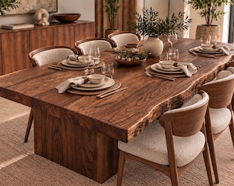 May include: A large rectangular dining table with a natural live edge wood grain surface and a solid block base, surrounded by six wooden chairs featuring curved backrests and textured cream-colored upholstered seats.