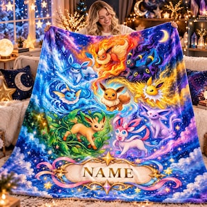 May include: A plush fleece blanket featuring a vibrant, colorful illustration of nine Eevee evolution characters set against a cosmic, starry sky background. At the bottom, a decorative scroll banner contains the placeholder text NAME.