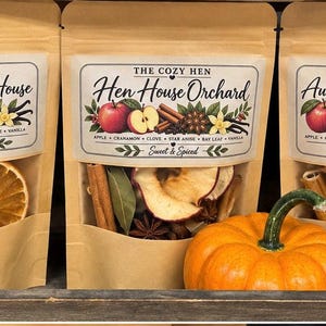 May include: Three kraft paper pouches labeled The Cozy Hen containing dried potpourri ingredients. The labels read Harvest at the HenHouse, Hen House Orchard, and Autumn on the Homestead, featuring illustrations of fruits, spices, and herbs.