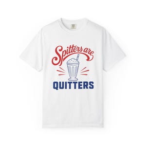 Könnte beinhalten: Ein weißes kurzärmeliges T-Shirt mit einem Grafikdruck, der in der Mitte einen blauen Milchshake zeigt. Über dem Milchshake steht in roter Schreibschrift "Spitters are" und darunter in blauer Schrift das Wort "QUITTERS".