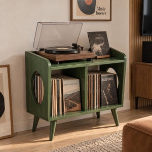 May include: A dark green wooden record player stand with four tapered legs and two circular side cutouts. The top surface holds a wood-grain turntable with a clear dust cover. Two interior shelves are filled with vinyl records and album covers.