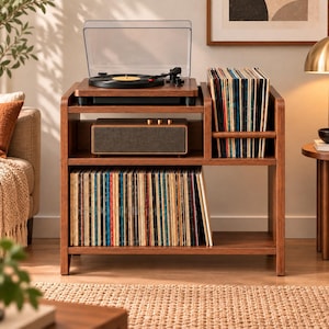 May include: A wooden media console featuring a top shelf with a record player, a middle shelf with a rectangular speaker, and a lower shelf filled with vinyl records. A vertical side compartment holds additional vinyl records in a row.