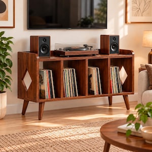 May include: A dark wood media console with four open storage compartments filled with vinyl records. The top surface holds two wooden speakers and a turntable with a clear cover. The console features diamond-shaped side cutouts.