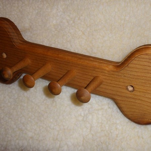 May include: Wooden dog bone shaped coat rack with five hooks. The rack is made of light brown wood and has a natural finish.