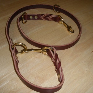 May include: A brown leather dog leash with a braided section and two brass clasps.