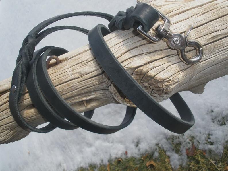 Pu&ograve; includere: Un guinzaglio in pelle nera caratterizzato da una sezione intrecciata e un moschettone girevole in metallo color argento. Il guinzaglio &egrave; realizzato con una cinghia di pelle piatta e include un piccolo rivetto metallico vicino all'impugnatura.