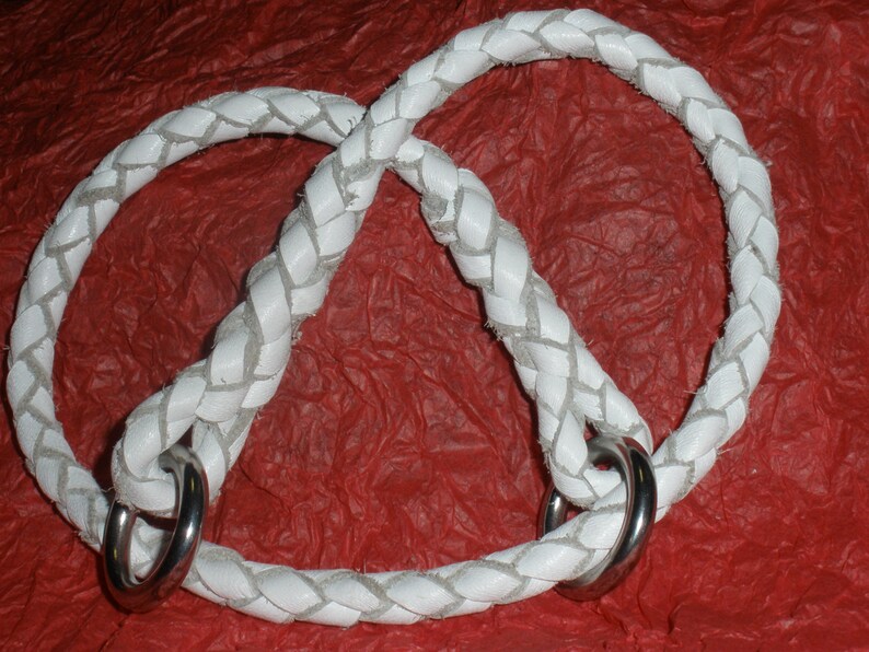 Pu&ograve; includere: Una corda intrecciata bianca formata ad anello, dotata di due anelli in metallo color argento lucido fissati alla base dove si incontrano le estremit&agrave; della corda. La trama intrecciata &egrave; visibile lungo tutta la lunghezza della corda.