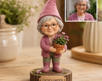 Peut inclure: Une figurine représentant une personne âgée aux cheveux gris avec des lunettes, portant un chapeau, un gilet et des bottes roses, tenant une petite plante en pot. La figurine repose sur un socle en bois avec l'inscription LUCIA'S GARDEN.
