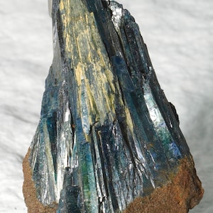 May include: A blue and tan mineral specimen with elongated, blade-like crystals. The piece features text VIV-001 and dimensions 39.8*42.7*67.7mm with a weight of 102.1g. The structure is vertical with a rough, brown base and shiny blue facets.