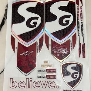 Könnte beinhalten: Ein Bogen mit Cricket-Schläger-Aufklebern, bestehend aus zwei großen schildförmigen Abziehbildern mit den Buchstaben SG in Weiß, einem dunkelroten strukturierten Hintergrund und dem Text believe. become. Kleinere Aufkleber enthalten den Text RR EDITIPON und THIS BAT COMES WITH SGIstr8bat SENSOR.