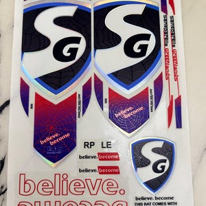 Könnte beinhalten: Ein Bogen mit Cricket-Schläger-Aufklebern, bestehend aus zwei großen schildförmigen Abziehbildern mit schwarzem Spinnennetzmuster, blau-roten Verläufen und den Buchstaben SG. Enthält den Text believe. become, Sanspareils Greenlands und RP LE.