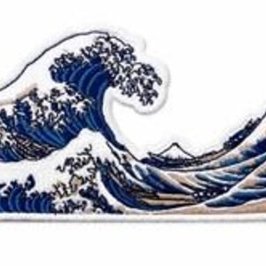 May include: An embroidered patch featuring a depiction of a large, cresting blue wave with white foam, inspired by Japanese art. The design includes a small, distant mountain peak in the background, rendered in shades of blue, white, and tan.