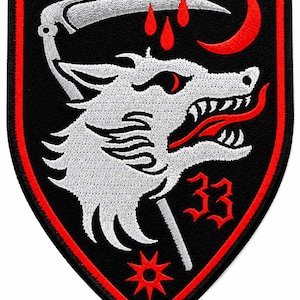 May include: A shield-shaped embroidered patch featuring a black background with a red border. The design includes a white wolf head, a silver scythe, three red blood drops, a red crescent moon, a red eight-pointed star, and the red number 33.