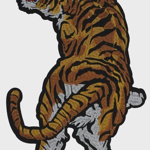 May include: An embroidered patch featuring a tiger in a standing, arched pose with its head turned back and mouth open. The tiger has orange fur with black stripes, white underparts, and a thick black border outlining the entire shape.
