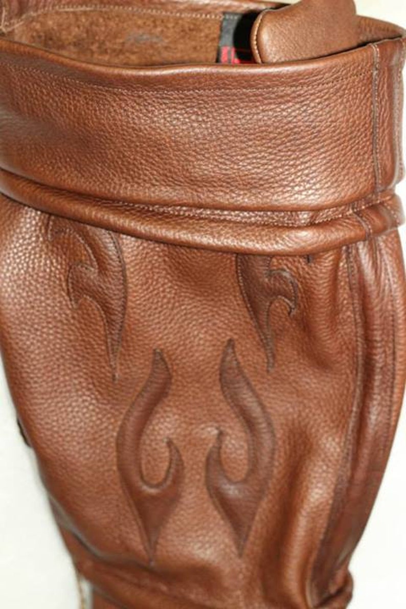 May include: Brown leather boot with a flame design. The boot has a fold-over top and a pointed toe.
