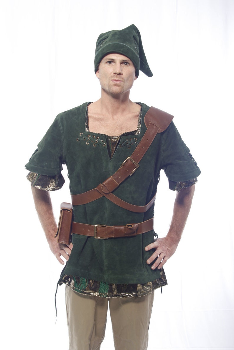 May include: A man wearing a green suede tunic with a brown leather belt and shoulder strap. He is also wearing a green hat with a pointed tip.