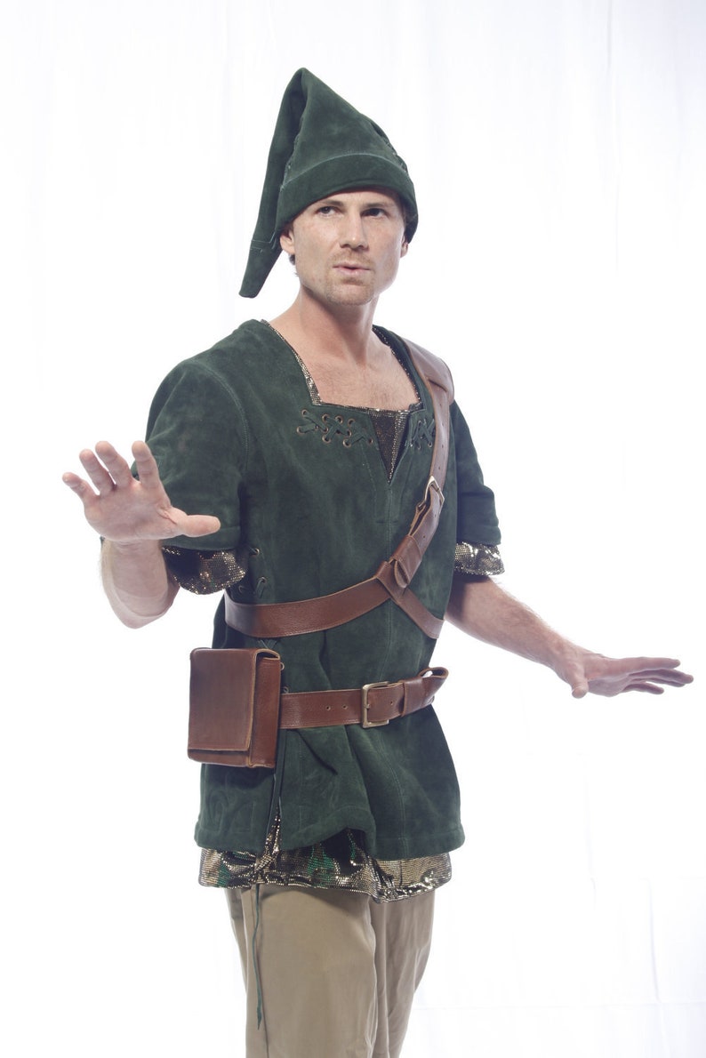 May include: A man wearing a green suede tunic with a brown leather belt and shoulder strap. He is also wearing a green suede hat and brown pants.