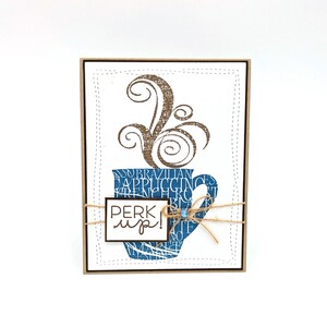 May include: A brown and blue card with a coffee cup design and the text "perk up!" on a tag. The coffee cup is filled with text and has steam rising from it.