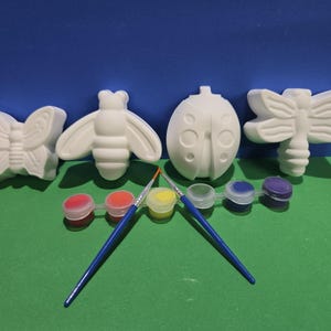 Peut inclure: Un ensemble de quatre figurines d'insectes en céramique blanche comprenant un papillon, une abeille, une coccinelle et une libellule. Le kit inclut une bande de six petits pots de peinture rouge, orange, jaune, bleu clair, bleu foncé et violet.