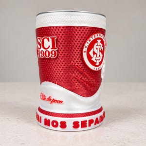 May include: A cylindrical red and white beverage holder featuring a textured mesh pattern. It displays the text SCI 1909, Clube do povo, and NADA VAI NOS SEPARAR, along with the S.C. Internacional circular logo in red and white on the side.