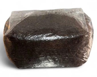 Pode incluir: Um bloco retangular de substrato orgânico granular castanho-escuro, fortemente comprimido e selado dentro de um saco de plástico transparente e flexível. O conteúdo parece ser uma mistura densa e uniforme de partículas de terra ou turfa.
