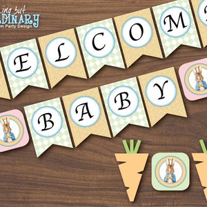 May include: A printable banner with the words "Welcome Baby" in a circle with a green and yellow checkered background. There are also four small images of Peter Rabbit in a circle with a pink and green background. There are two orange carrots with green tops.