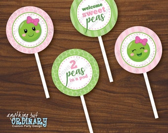 Op de afbeelding: Drie ronde lollystokjes in roze en groen met een erwtenpeulthema. De eerste stok zegt "welcome sweet peas". De tweede stok zegt "2 peas in a pod". De derde stok heeft een cartoon-erwt met een roze strik.