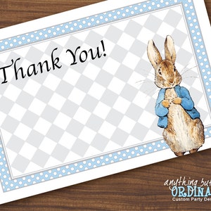 May include: A white thank you card with a blue and white polka dot border. The card has a gray and white checkered background with a cartoon illustration of Peter Rabbit wearing a blue jacket. The text "Thank You!" is written in black cursive.