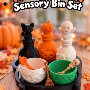 Könnte beinhalten: Ein Halloween-Sensorik-Set bestehend aus einem schwarzen Tablett mit drei Flaschen, die mit einer schwarzen Katze, einem orangefarbenen Kürbis und einem weißen Geist verziert sind. Zwei Schalen, eine weiße Mumie und eine grüne, enthalten Löffel.