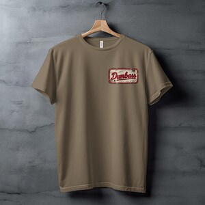 Tan t-shirt with a distressed rectangular patch reading "Dumbass" in red lettering.