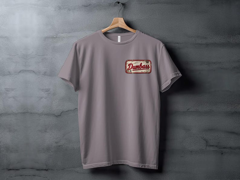Gray t-shirt with a red and white "Dumbass" patch on the left chest.