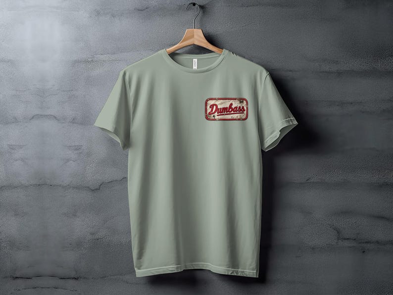 Light green t-shirt with a distressed "Dumbass" logo patch on the left chest.