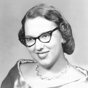 Descarga digital de una mujer de los años 50 con un lápiz labial sonriente, vestido de satén a la moda, gafas de ojo de gato de los años 50, fotografía antigua retro, foto vintage, imagen imprimible