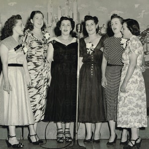 Descarga digital de fotografías antiguas: mujeres músicas de los años 50 en un coro de quinteto de pie en el escenario y cantando canciones para un concierto frente a un micrófono