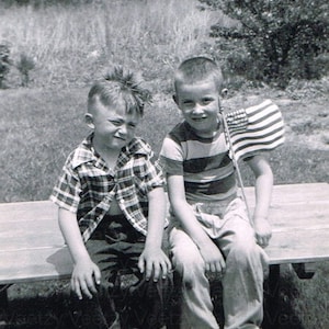 Vaterländischen druckbaren Download - 1950s kleine Jungen lächelnd, beste Freunde schwenken eine amerikanische Flagge aka Old Glory am vierten Juli