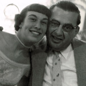 Foto d'epoca con download digitale: padre felice di una giovane sposa che abbraccia la sua bellissima figlia e sorride durante il suo matrimonio, istantanea degli anni '50