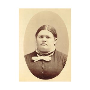May include: A black and white portrait photograph of a woman wearing a dark dress with a white bow tie. She has a serious expression on her face.