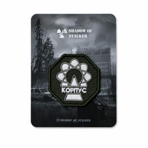 May include: An octagonal embroidered patch featuring a white atomic symbol graphic and the Cyrillic text KOPNYC on a black background. The patch is mounted on a display card with the text SHADOW OF STALKER and a radiation symbol icon.