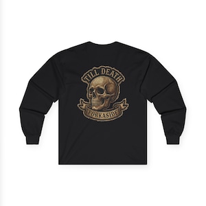 May include: A black long-sleeve shirt featuring a graphic print on the chest. The design displays a beige human skull centered within a circular frame, with a banner below containing the text TILL DEATH FORKASIDE in a bold, serif font.