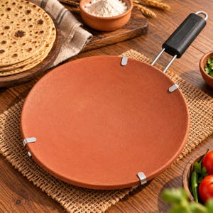 Peut inclure: Une poêle de cuisson ronde et plate en terre cuite avec une surface lisse brun rougeâtre. La poêle est fixée par quatre clips en métal argenté reliés à une poignée noire avec un cadre métallique, conçue pour chauffer des pains plats.