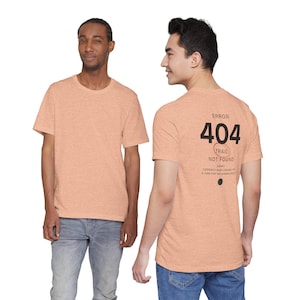 May include: A peach-coloured short-sleeve t-shirt with a crew neck. The front is plain, while the back features black text that reads ERROR 404 TRAIL NOT FOUND, with additional smaller text below and a small black circle graphic near the bottom hem.