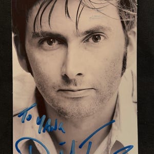 May include: A black and white portrait photograph of David Tennant, featuring a blue ink autograph across the bottom. The handwritten inscription reads To Yada, followed by a large, stylized signature in blue marker over the lower portion of the image.
