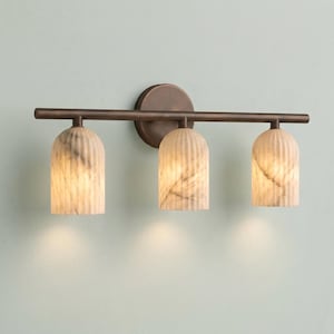 May include: A three-light vanity wall fixture featuring a dark bronze horizontal bar and a circular wall mount. The fixture includes three downward-facing, ribbed, dome-shaped glass shades with a marbled white and grey pattern throughout.