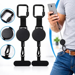 May include: Two black retractable badge reels with carabiner clips and T-shaped attachments. Each unit features a circular housing, a nylon strap, and a metal carabiner. The device is shown attached to a belt loop, extending a cord to a smartphone.