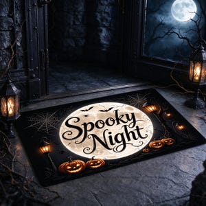Peut inclure: Un paillasson rectangulaire présentant une grande pleine lune lumineuse au centre avec le texte Spooky Night écrit en lettres cursives noires. Le motif comprend des citrouilles orange, des silhouettes de chauves-souris, des toiles d'araignée.