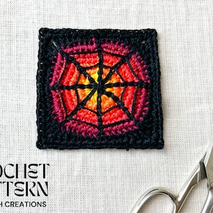 Puede incluir: Un cuadrado de ganchillo con un diseño de telaraña en tonos rojos, naranjas y amarillos, enmarcado por un borde negro. El texto "CROCHET PATTERN" y "SARAVAH CREATIONS" es visible. También hay unas tijeras en la imagen.