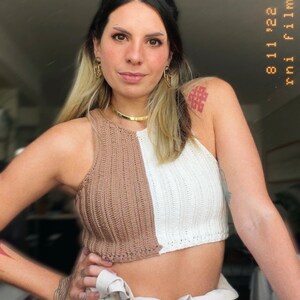 May include: A brown and white crocheted halter top with a contrasting color design. The top is cropped and has a relaxed fit.
